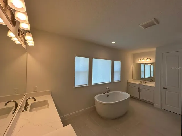 a bathroom with a granite countertop sink and mirror bathtub