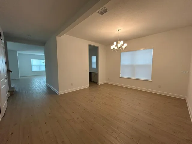 an empty room with chandelier fan and windows