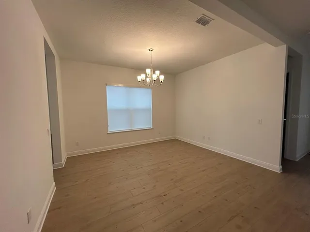an empty room with a chandelier fan and windows