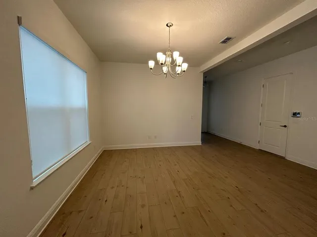an empty room with wooden floor and chandelier