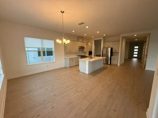 a view of a kitchen with kitchen island a counter top space a sink stainless steel appliances and cabinets