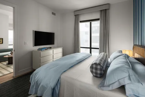 a bedroom with a bed tv and a window