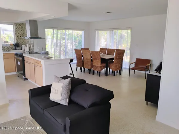 a living room with couches chairs and a dining table with wooden floor