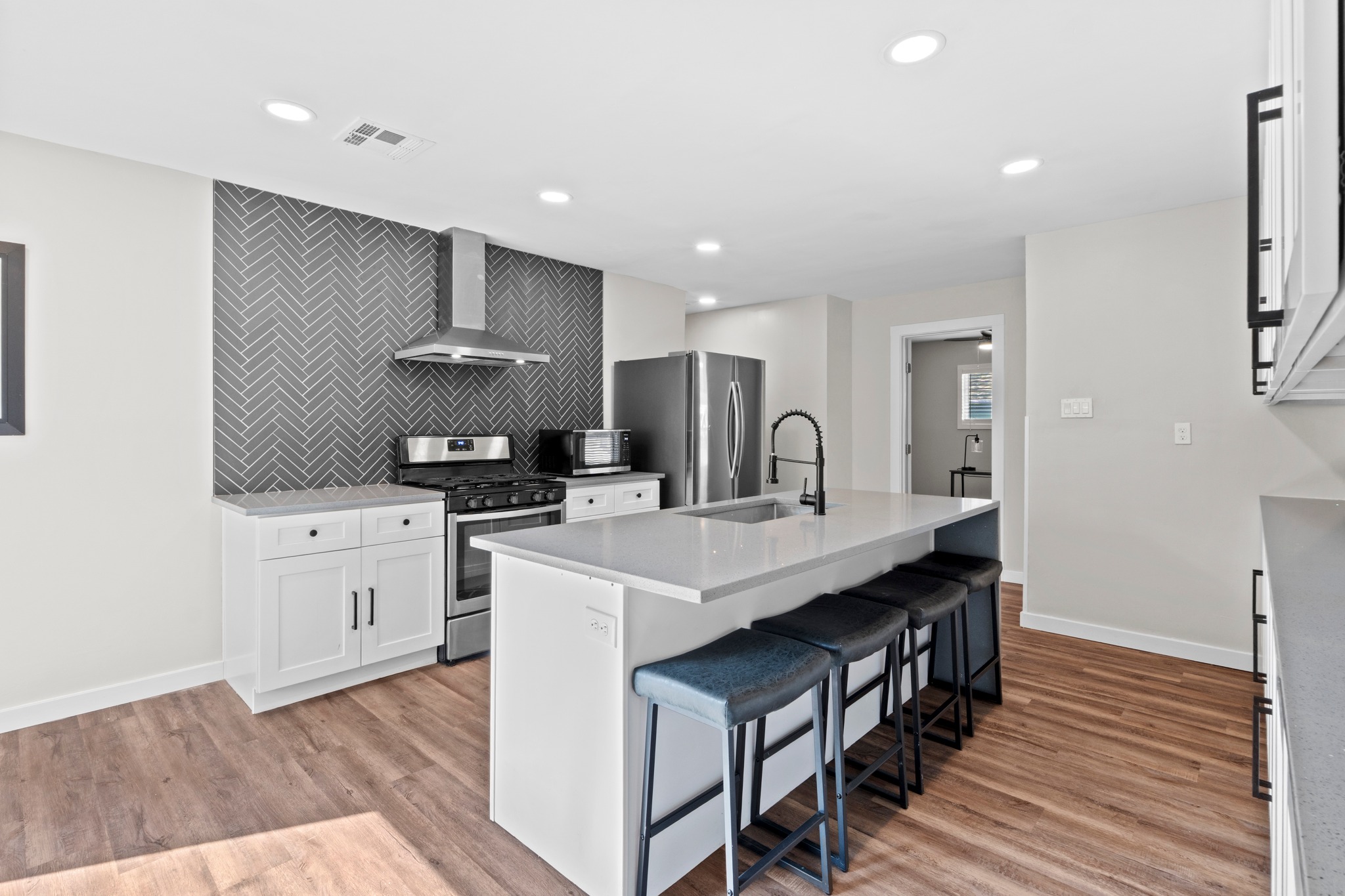 11811 Rotherham Drive Austin, TX 78754 - Photo 13 of 37 A contemporary kitchen features a spacious island with bar seating, integrated sink, and modern stainless steel appliances.
