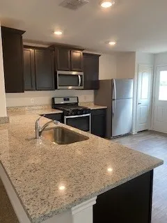 a kitchen with stainless steel appliances granite countertop a sink a stove a refrigerator a washer dryer and wooden cabinets