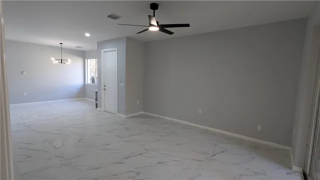 en empty room with windows and chandelier fan