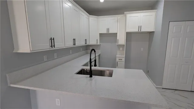 a view of a kitchen with refrigerator and white wooden cabinets