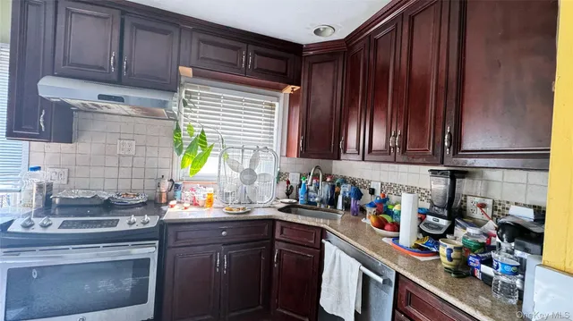 a kitchen with stainless steel appliances wooden cabinets sink and a stove top oven