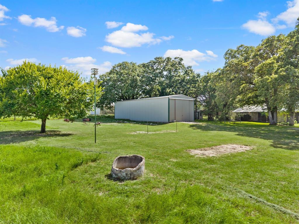 515 New Highland Road Springtown, TX 76082 - Photo 31 of 38 Expansive green lawn with mature trees and a large metal outbuilding