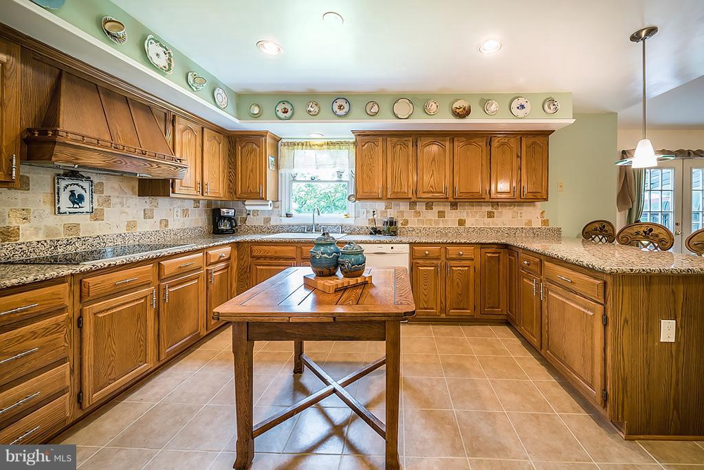216 Serene Road Friendship, MD 20758 - Photo 16 of 29 a kitchen with stainless steel appliances granite countertop wooden cabinets a sink a stove a kitchen island and chairs