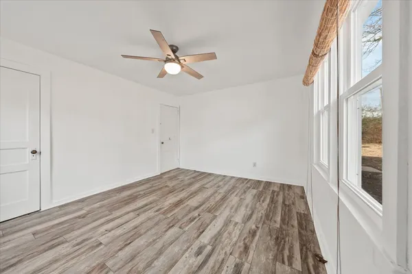 a view of empty room with wooden floor and fan