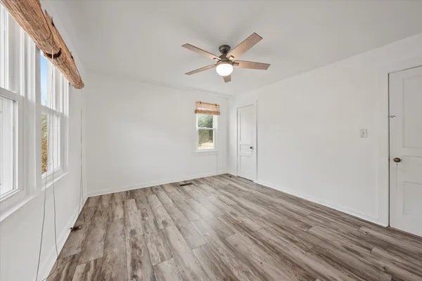 a view of empty room with wooden floor and fan