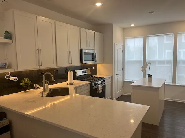 a large kitchen with kitchen island a large counter top space a sink a stove and a refrigerator