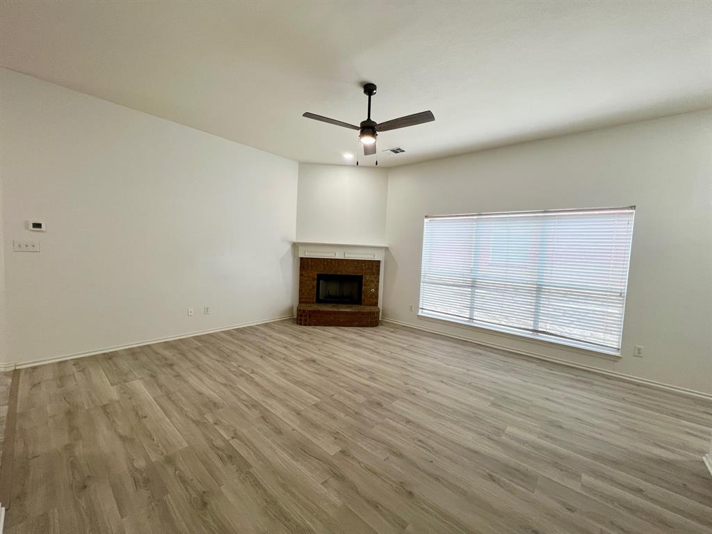 1348 Riley Drive Carrollton, TX 75007 - Photo 3 of 11 an empty room with wooden floor ceiling fan and windows