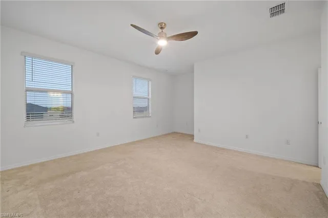 an empty room with ceiling fan and windows