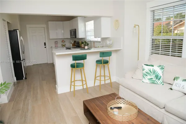 a living room with stainless steel appliances furniture a rug and a large window