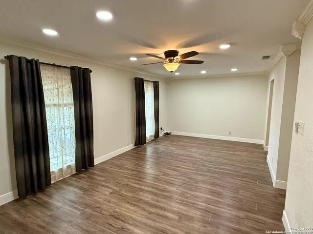 an empty room with wooden floor and a ceiling fan
