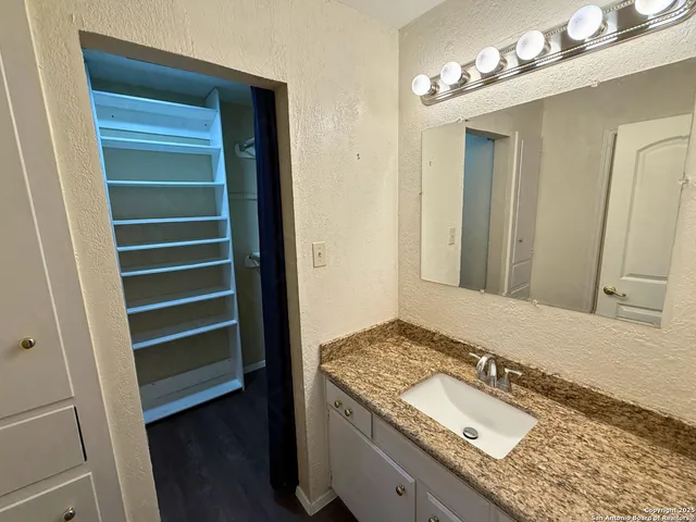 a bathroom with a granite countertop sink and a mirror
