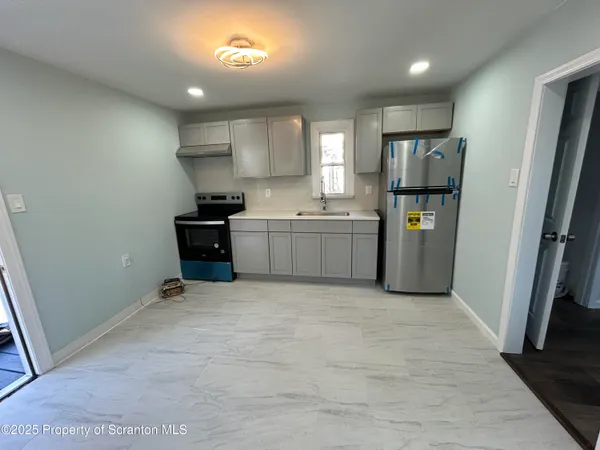 a view of a kitchen with fridge and wooden floor