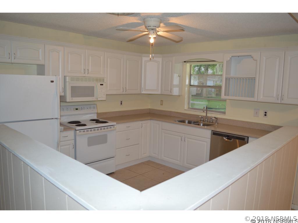 1867 Pine Tree Drive Edgewater, FL 32141 - Photo 2 of 10 a kitchen with granite countertop a sink stainless steel appliances and white cabinets