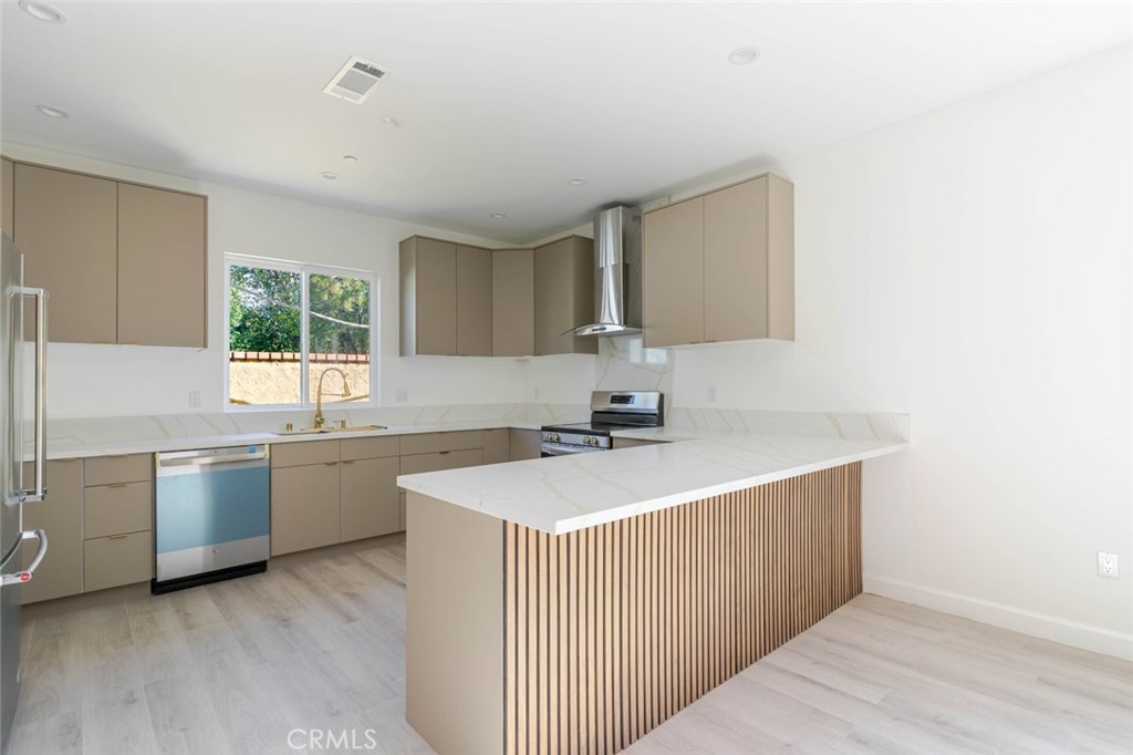 17426 Roscoe Boulevard Northridge, CA 91325 - Photo 10 of 28 a kitchen with stainless steel appliances granite countertop a sink dishwasher a stove and a refrigerator with wooden floor