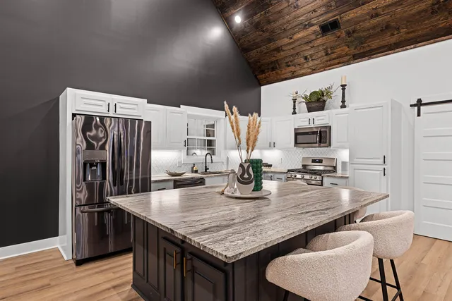 a kitchen with granite countertop kitchen island stainless steel appliances a sink stove and refrigerator