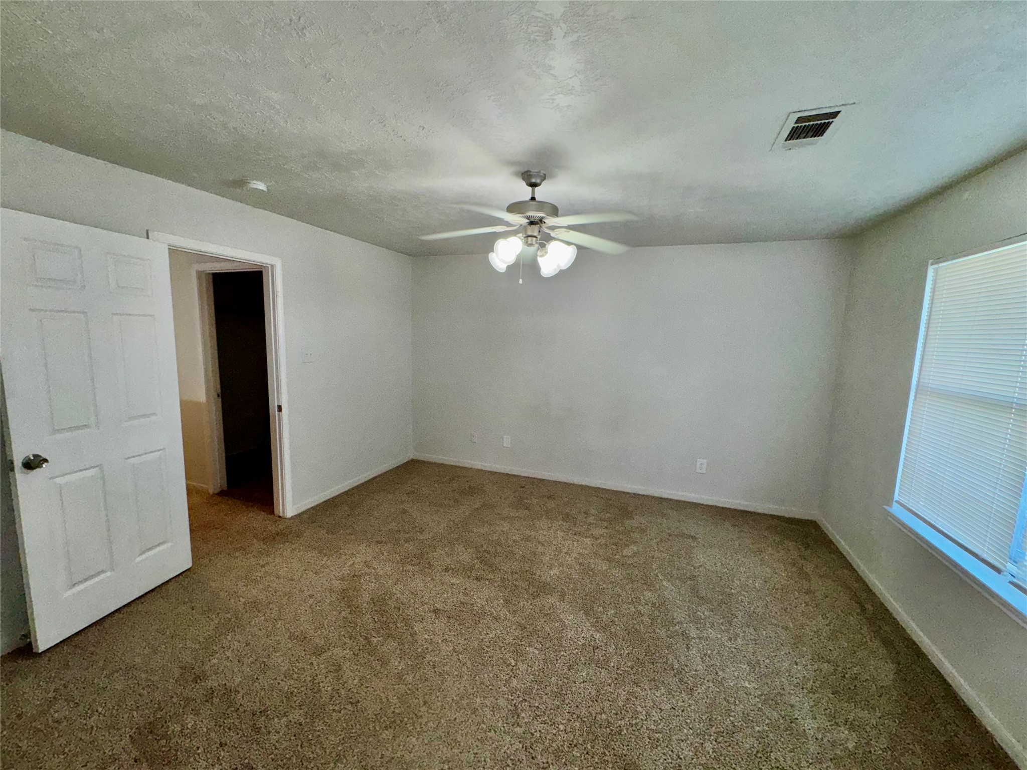 15931 Winston Point Lane Houston, TX 77084 - Photo 11 of 15 an empty room with a chandelier fan and windows