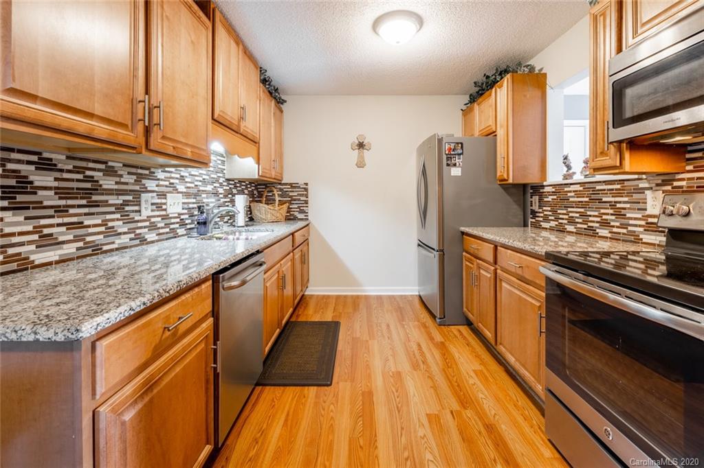 5523 Hornaday Road, Unit G Greensboro, NC 27409 - Photo 6 of 20 a kitchen with stainless steel appliances granite countertop a stove and a refrigerator