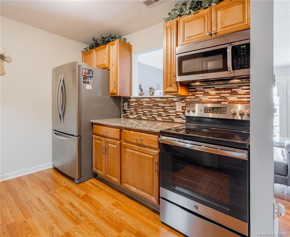 5523 Hornaday Road, Unit G Greensboro, NC 27409 - Photo 7 of 20 a kitchen with stainless steel appliances granite countertop a stove microwave and refrigerator