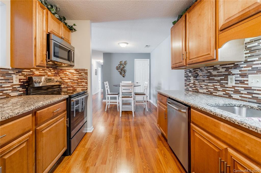 5523 Hornaday Road, Unit G Greensboro, NC 27409 - Photo 8 of 20 a kitchen with stainless steel appliances wooden floors wooden cabinets and sink