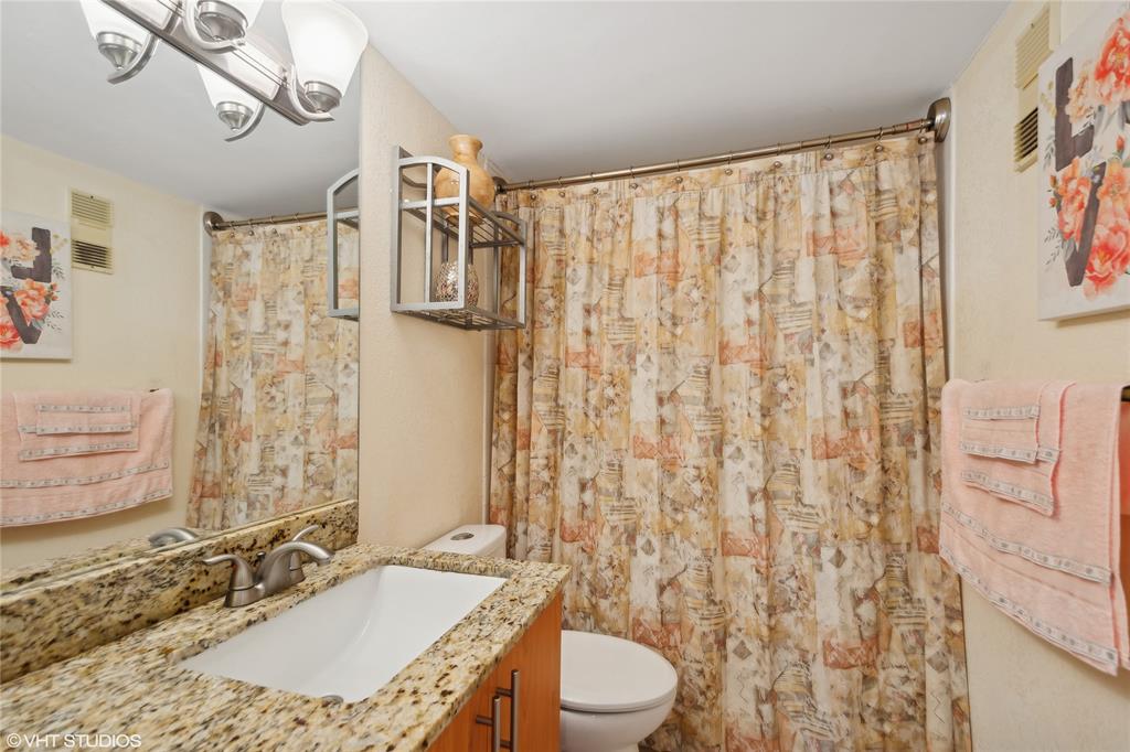 3940 Inverrary Boulevard, Unit 403A Lauderhill, FL 33319 - Photo 21 of 34 a bathroom with a granite countertop sink a toilet a mirror and shower curtain