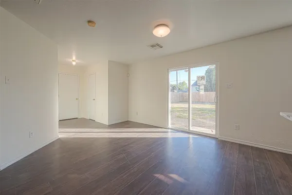 an empty room with wooden floor and windows with curtains