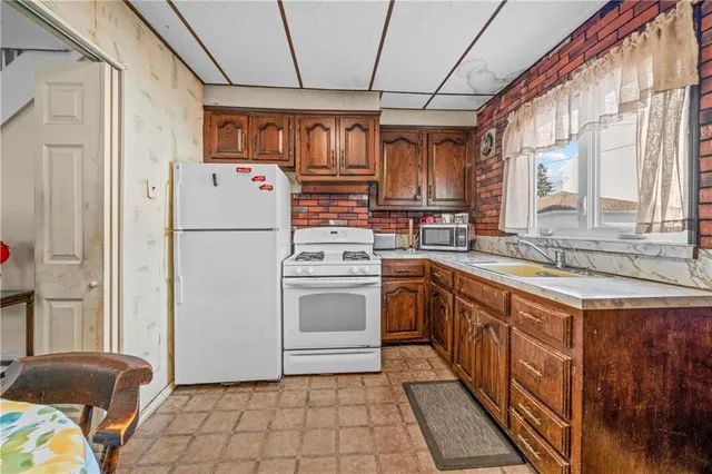 a kitchen with stainless steel appliances granite countertop a refrigerator a sink dishwasher a stove with white cabinets and wooden floor