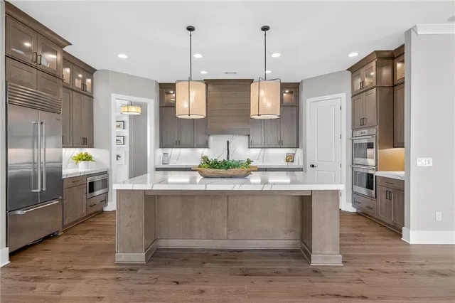 a kitchen with stainless steel appliances granite countertop a sink a stove and a wooden floors