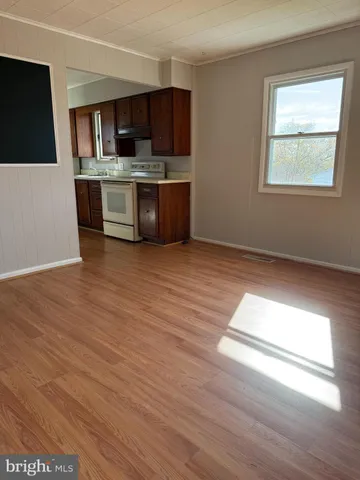 a view of kitchen with stainless steel appliances wooden floor and window