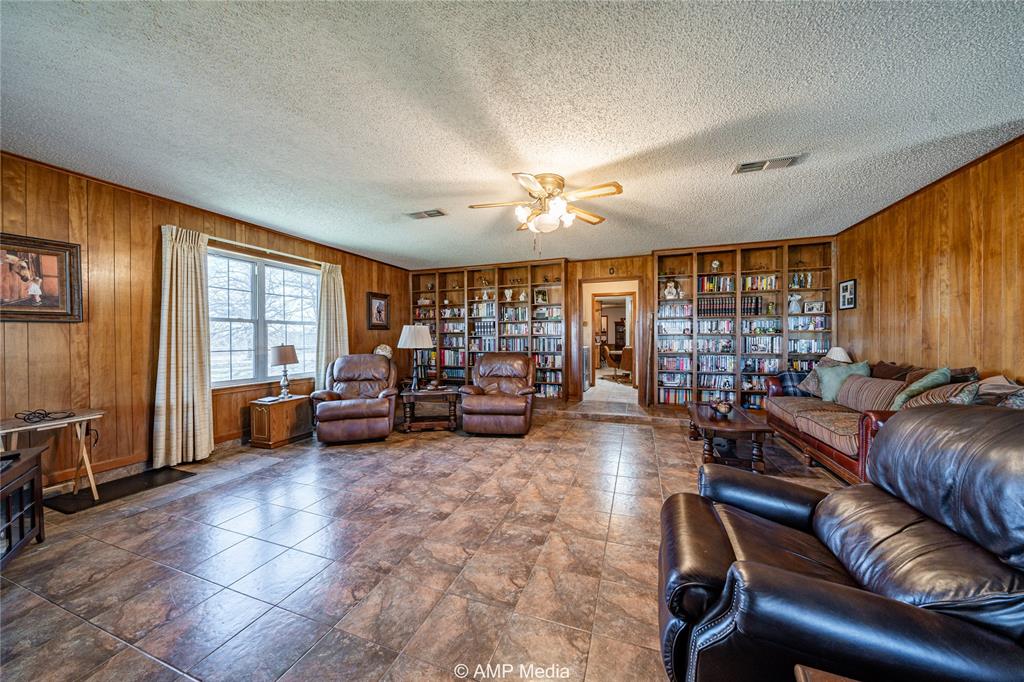 1992 Sand Flat Road Jacksboro, TX 76458 - Photo 25 of 36 Living room with ceiling fan, a textured ceiling, and wood walls