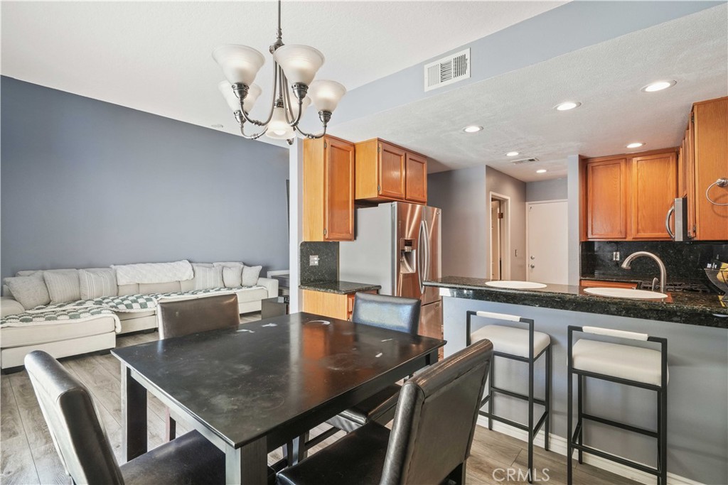 28345 Seco Canyon Road, Unit 97 Saugus, CA 91390 - Photo 10 of 38 a kitchen with stainless steel appliances granite countertop a dining table chairs and a refrigerator