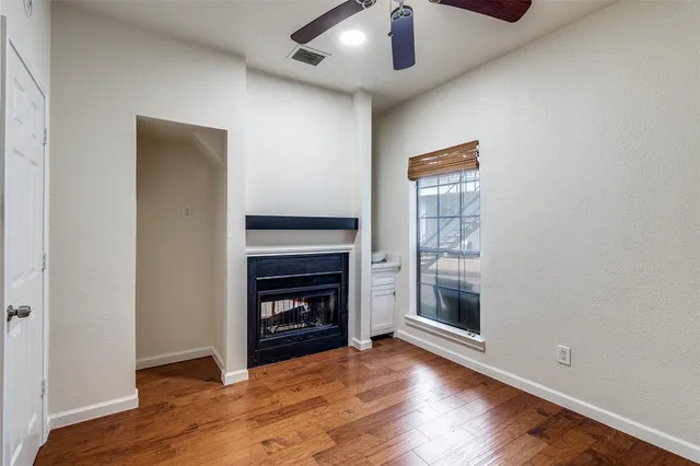 an empty room with wooden floor a fireplace and windows
