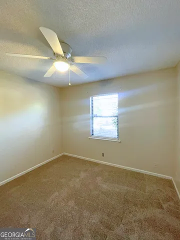 an empty room with a fan & a window