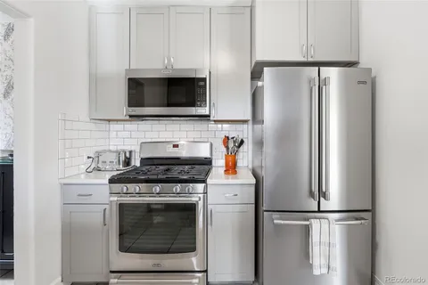 a kitchen with stainless steel appliances white cabinets white stove a microwave and a refrigerator