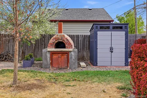 a view of brick house with a small yard and large tree