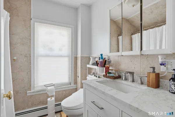 a bathroom with a granite countertop sink a toilet and a shower