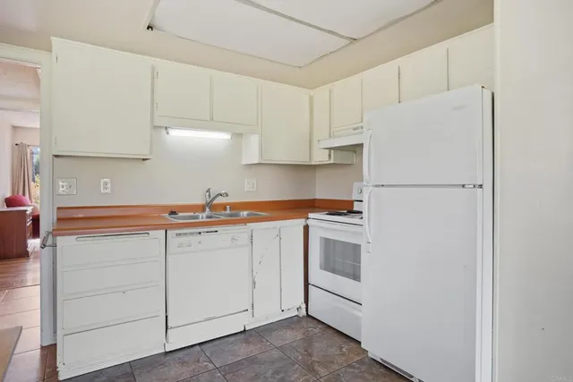 a kitchen with cabinets appliances a sink and a refrigerator