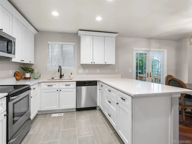 a kitchen with granite countertop a sink a stove a refrigerator and white cabinets