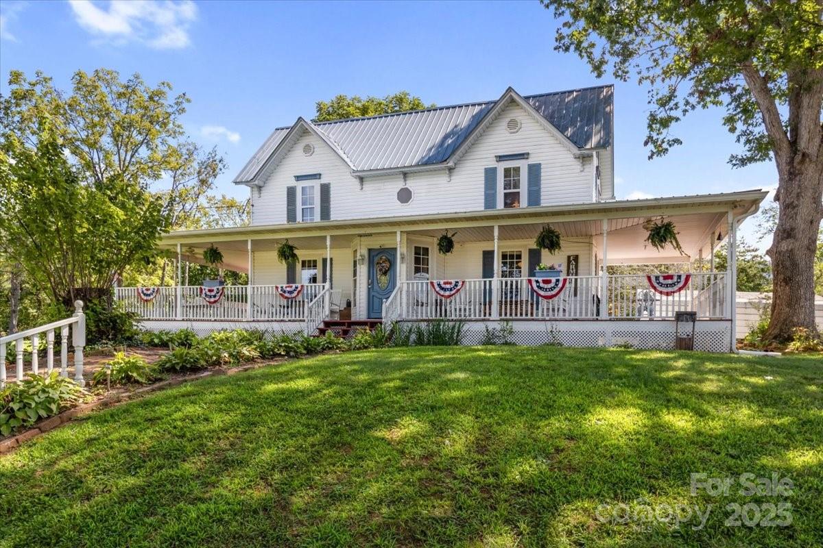a view of a white house with a big yard and large trees