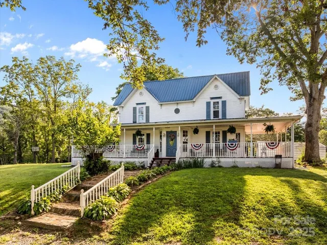 a view of a house with a big yard and large trees
