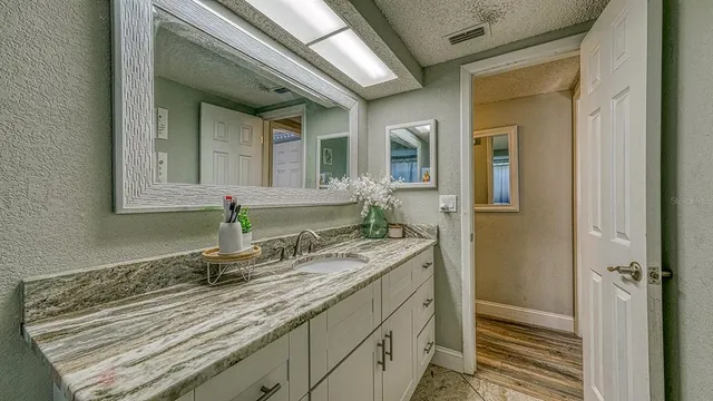 a bathroom with a granite countertop sink and a mirror