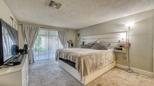 a bedroom with a bed and a flat tv screen on dresser