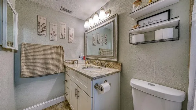 a bathroom with a granite countertop toilet sink and mirror