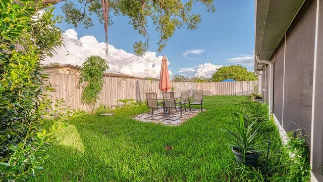 a backyard of a house with plants and large tree